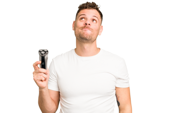 Young caucasian man holding a razor isolated dreaming of achieving goals and purposes