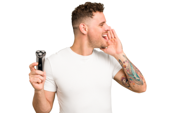 Young caucasian man holding a razor isolated shouting and holding palm near opened mouth.