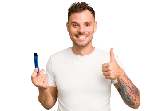Young caucasian man holding a electronic cigarette isolated smiling and raising thumb up