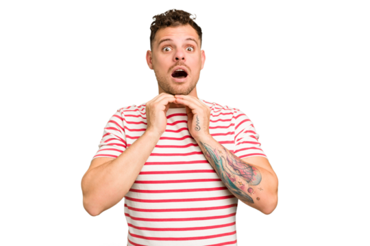 Young caucasian handsome man isolated praying for luck, amazed and opening mouth looking to front.