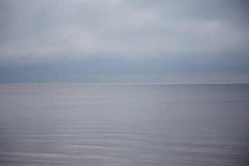 Transparent sea water surface with cloudy sky on a winter day, selective focus