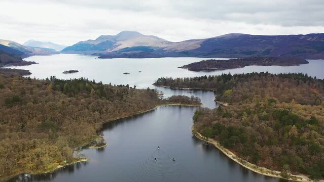 Aerial drone angle of boats travelling through the narrows on Loch Lomond, Scotland, with Luss and Ben Lomond in the background in early spring.