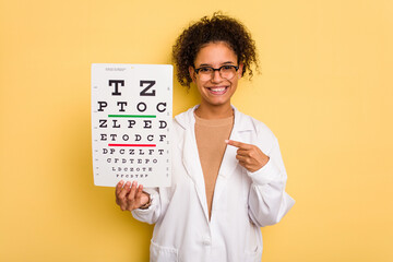 Young brazilian oculist woman isolated smiling and pointing aside, showing something at blank space.