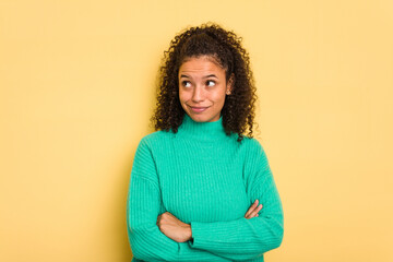 Young Brazilian curly hair cute woman isolated on yellow background dreaming of achieving goals and purposes