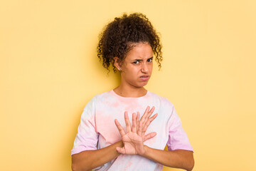 Young Brazilian curly hair cute woman isolated on yellow background doing a denial gesture
