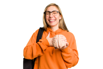 Young student caucasian woman holding a brain isolated laughs out loudly keeping hand on chest.