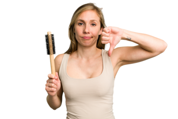 Young caucasian woman using an hair comb isolated showing a dislike gesture, thumbs down. Disagreement concept.
