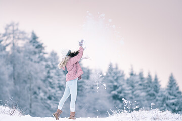 Welcome winter,happy girl, woman enjoys winter and plays with snow in the middle of a snowy landscape,in warm clothes with a hat and gloves,cold and Christmas atmosphere,photo in snowy nature,healthy