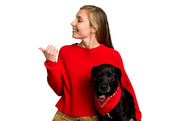 Young caucasian woman and her dog isolated points with thumb finger away, laughing and carefree.