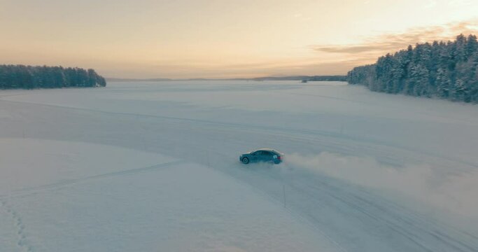 Drifting car speeding on corner on Norbotten woodland ice lake aerial tracking view at sunrise