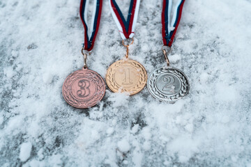 Gold, silver and bronze medals with numbers on snow background for winners. Medal with tricolor ribbon .Winter olympic games - obrazy, fototapety, plakaty