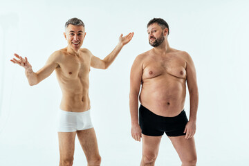 Fototapeta na wymiar Two multiethnic men posing for a male edition body positive beauty set. Shirtless guys with different age, and body wearing boxers underwear