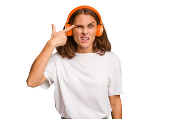 Young caucasian woman listening to music with headphones isolated showing a disappointment gesture with forefinger.