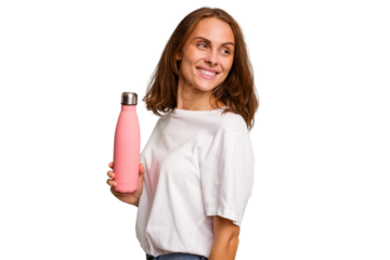 Young caucasian woman holding a pink thermo isolated looks aside smiling, cheerful and pleasant.