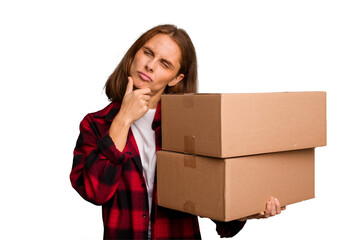 Young caucasian woman moving while picking up a box full of things isolated looking sideways with doubtful and skeptical expression.