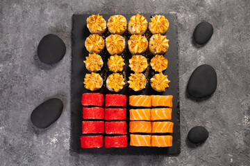 Top view sushi set. Philadelphia roll, california, unagi with fresh ingredients on black background. Sushi menu. Japanese asian food.