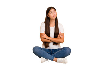 Young asian woman sitting on the floor cutout isolated dreaming of achieving goals and purposes