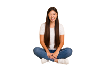 Young asian woman sitting on the floor cutout isolated funny and friendly sticking out tongue.