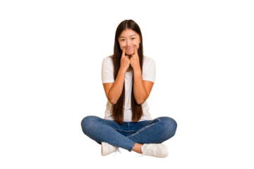 Young asian woman sitting on the floor cutout isolated doubting between two options.