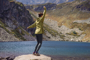 Happy excited and hiking woman dancing in mountain outdoors with lake landscape background
