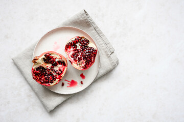 Obraz na płótnie Canvas Draufsicht auf einen halbierten rohen Granatapfel mit Kernen auf einem Teller. Gesundes Obst.