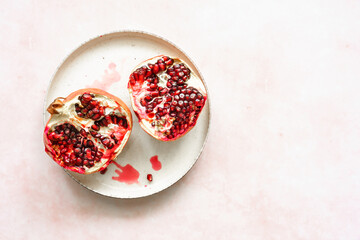 Draufsicht auf zwei Granatapfel Hälften mit Kernen auf einem rosa Hintergrund. Gesunde Ernährung.