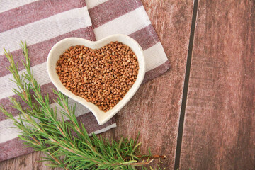 small grains of natural brown buckwheat in a decorative plate in the form of a heart