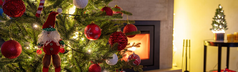 Christmas banner. Xmas tree decoration and lights close up, burning fireplace background.