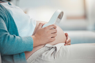 Fototapeta premium Relax, pregnant woman and headphones on stomach, music playing for baby in living room. Pregnancy, earphones on belly and technology, woman on sofa streaming audio sound for child listening in utero.