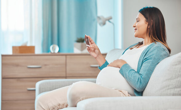 Pregnant, ultrasound and baby with a mother in the living room, sitting on a sofa in her home alone. Happy, smile and pregnancy with a woman looking a photograph of her infant in the house lounge