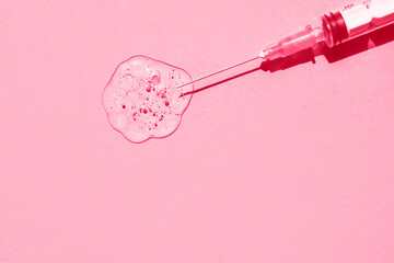 Sterile medical syringe and drop of gelatinous liquid on pink background. Demonstration of colors...
