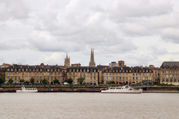 Obraz premium kathedrale von bordeaux hinter häuserzeile vom fluss aus