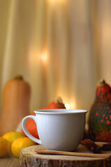 Cup of tea or coffee, seasonal spices, bowl of cookies, blanket, pumpkins, colorful leaves, books and tangerines on wooden table. Cozy hygge at home. Selective focus.