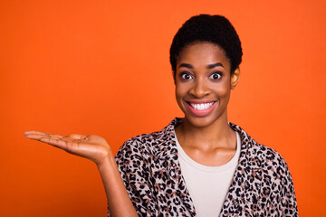 Portrait of cheerful person arm palm demonstrate empty space promotion isolated on orange color background