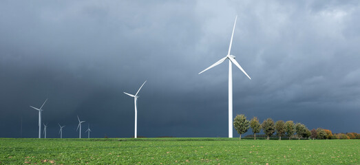 dark threatening grey sky and white wind turbines in belgium - 552044510
