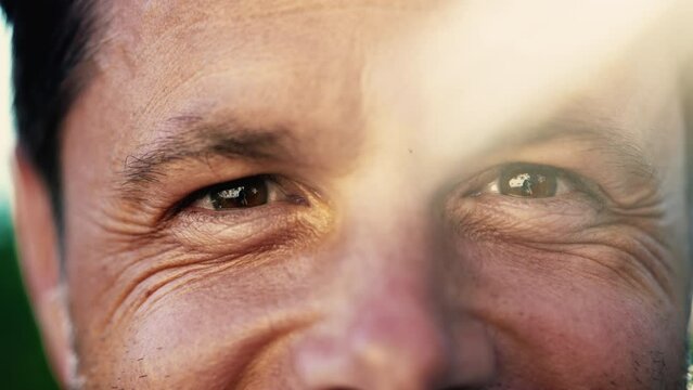 Portrait of a smiling man with wrinkles. Macro Close Up of male person with lens flare sunlight outdoors. Happy emotion expressio