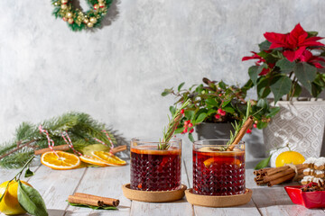 Fototapeta na wymiar Mulled wine in glasses on white wooden table. Hot winter drink with wine, spices and fruit in Christmas decoration. Copy space.