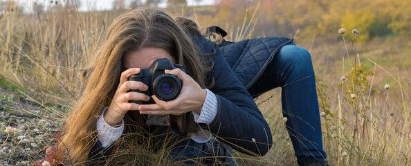 A girl with a camera in her hands in a funny pose makes a frame. Paparazi with a camera in his...