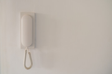 White intercom handset on a white wall. Close-up. 