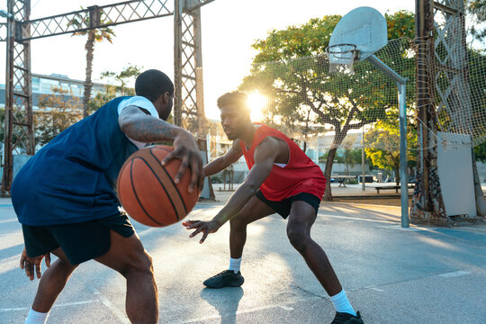 Young basketball players training at the court. Cinematic look image of friends practicing shots and slam dunks in an urban court