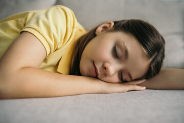 Obraz premium tired preteen girl sleeping on sofa at home