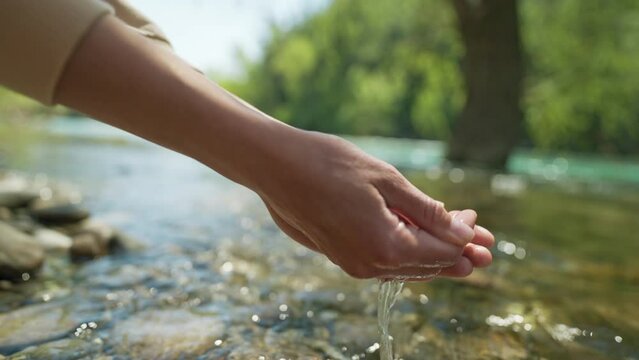 close up slow motion female hands taking fresh cold clean water in palms from mountain river. wide angle view, focus on palms. clean and safety invironment concept. water resources, earth, environment
