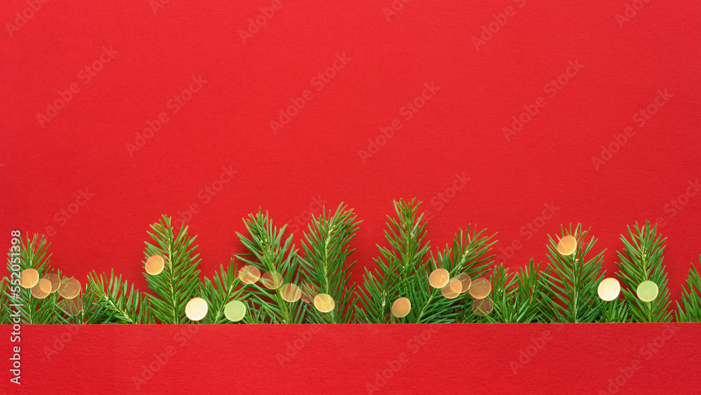 Poster Christmas frame made of Christmas tree branches with bokeh lights on a plain paper red background, copy space