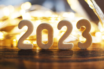 wooden number 2023 onchristmas beautifull shiny gold background. sparkle festive blurred bokeh