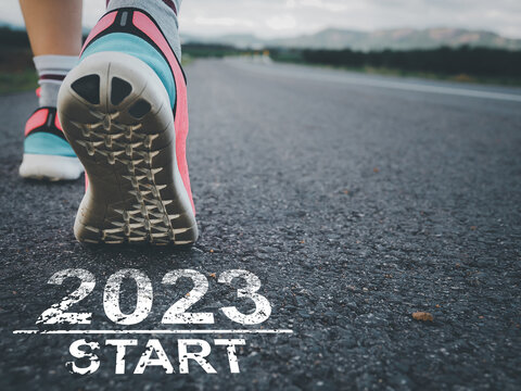 Taking off to start 2023. Female sprinter athlete preparing to run on the road with text on the road.