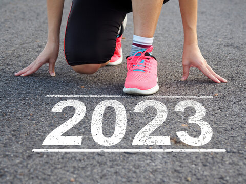 New year 2023 Female athlete running on the road with text Start 2023 on the road. Running towards goal. achieving new goals new challenge there is light in the picture