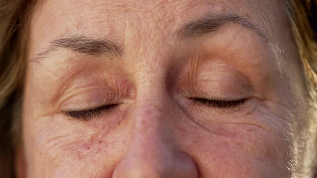 Wrinkled Senior woman closing eyes in meditation and contemplation. Macro close up of an older female person with eyes closed