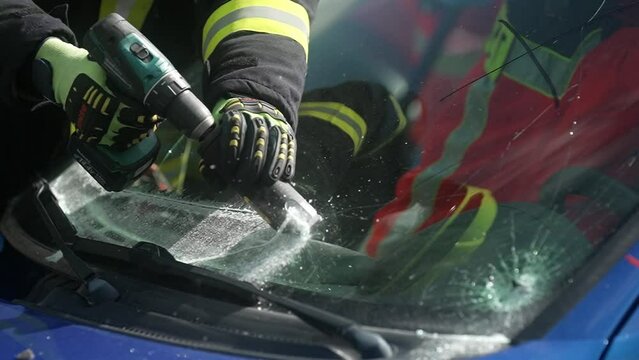 Cutting windshield during rescue operation of firefighters after a car accident in slow motion