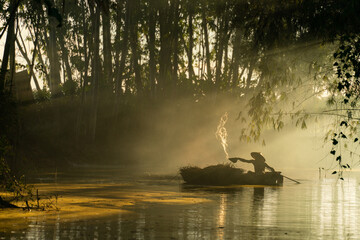 Photo of a local asian old man male boatman wearing conical hat rowing a small wooden boat across a...