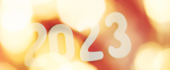 wooden number 2023 on christmas shiny gold and red background. sparkle festive blurred bokeh
